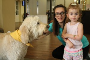 Lilly and Toni relax with a Hand in Paw therapy dog.