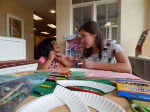 Abbie (left) helps one of the children make a craft.