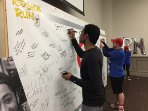 Two men sign the Heroes Wall, where runners can leave messages of encouragement for RMHCA families.
