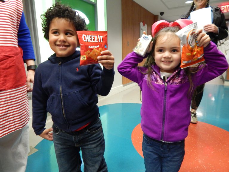 Two children show off the snacks they chose from the Happy Wheels Cart.