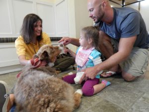 Daddy and daughter enjoy a visit from Hand in Paw.