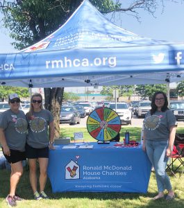 Intern stands (right) underneath RMHCA tent with 2 other RMHCA staff (left).