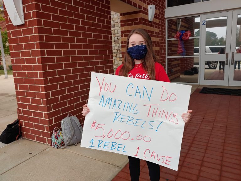 Student holds a sign promoting 1 Rebel 1 Cause