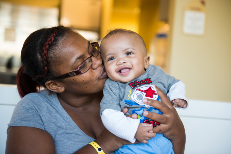 Mother kisses her infant son on the cheek