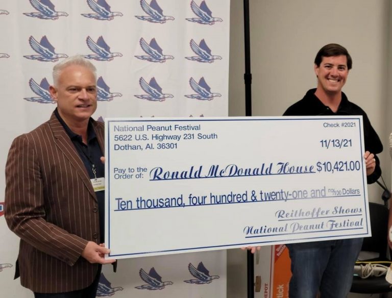 Two men hold up a presentation check representing a $10,421 donation from the National Peanut Festival to RMHCA