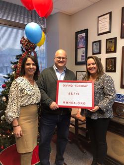 two women stand with a man who is holding a sign that says Giving Tuesday rmhca.org