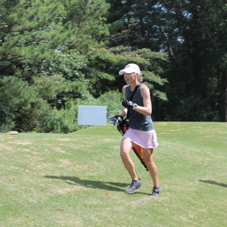 A woman in golfing clothing sprints across the green