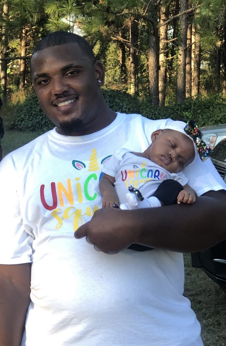 A woman, man, toddler girl and infant girl wearing matching birthday themed tees