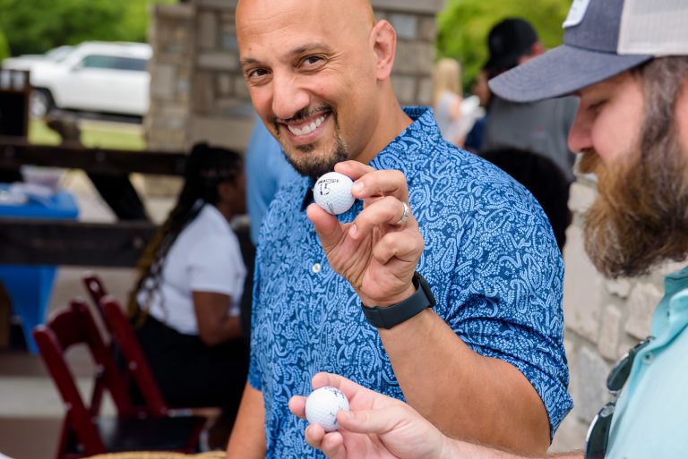 A man holds up a golf ball
