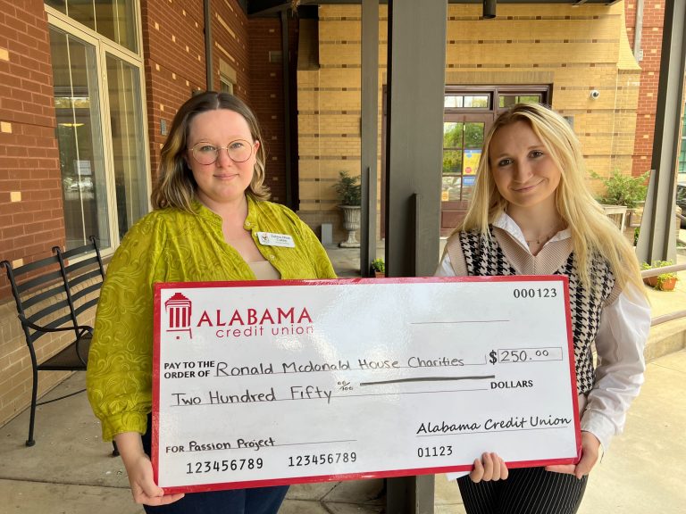 two women hold a display check with a donation for $250