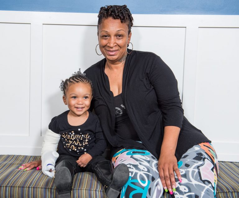 A mother and daughter sit together on a bench