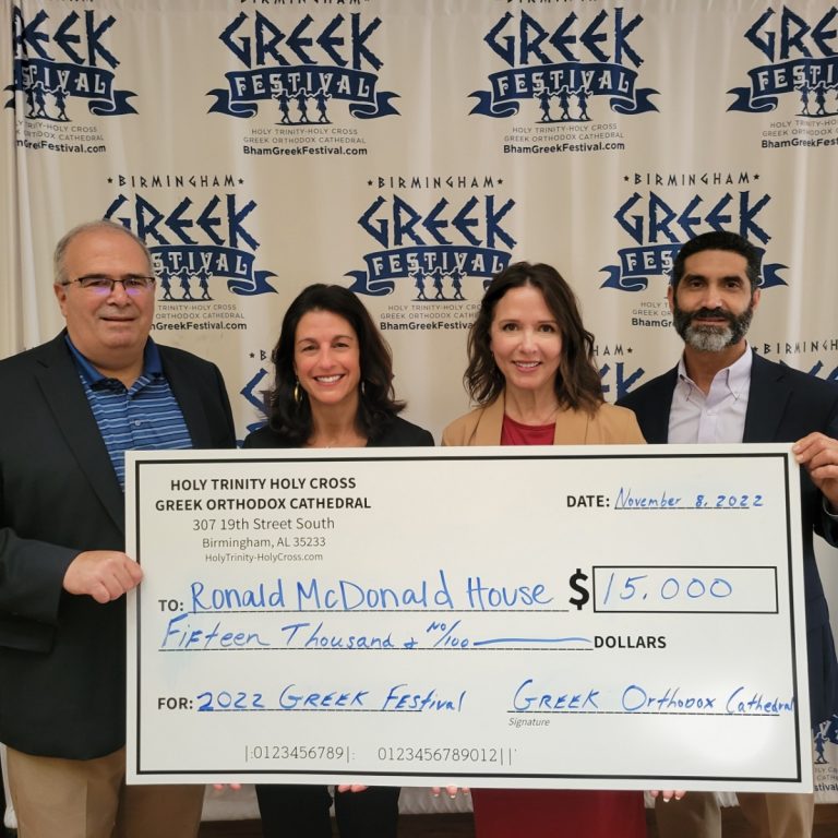 Four people gather around a presentation check representing $15,000