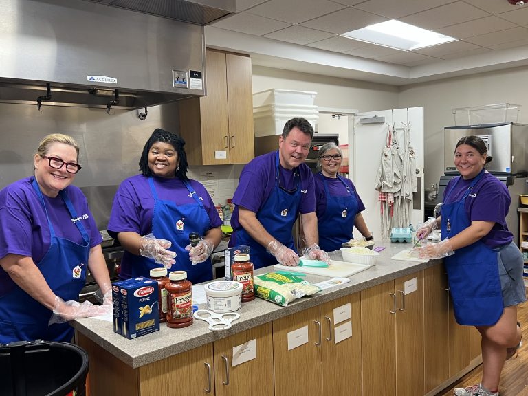 Four women and a man cook in a kitchen