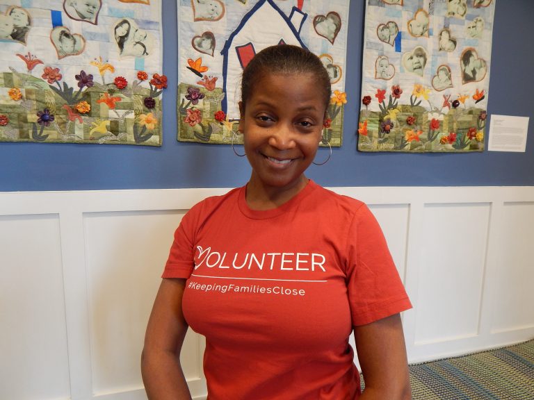A woman wears a red shirt with the word volunteer
