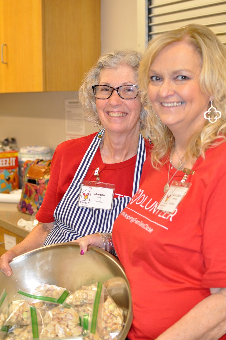 Two women wear red t-shirts with the word volunteer on the front