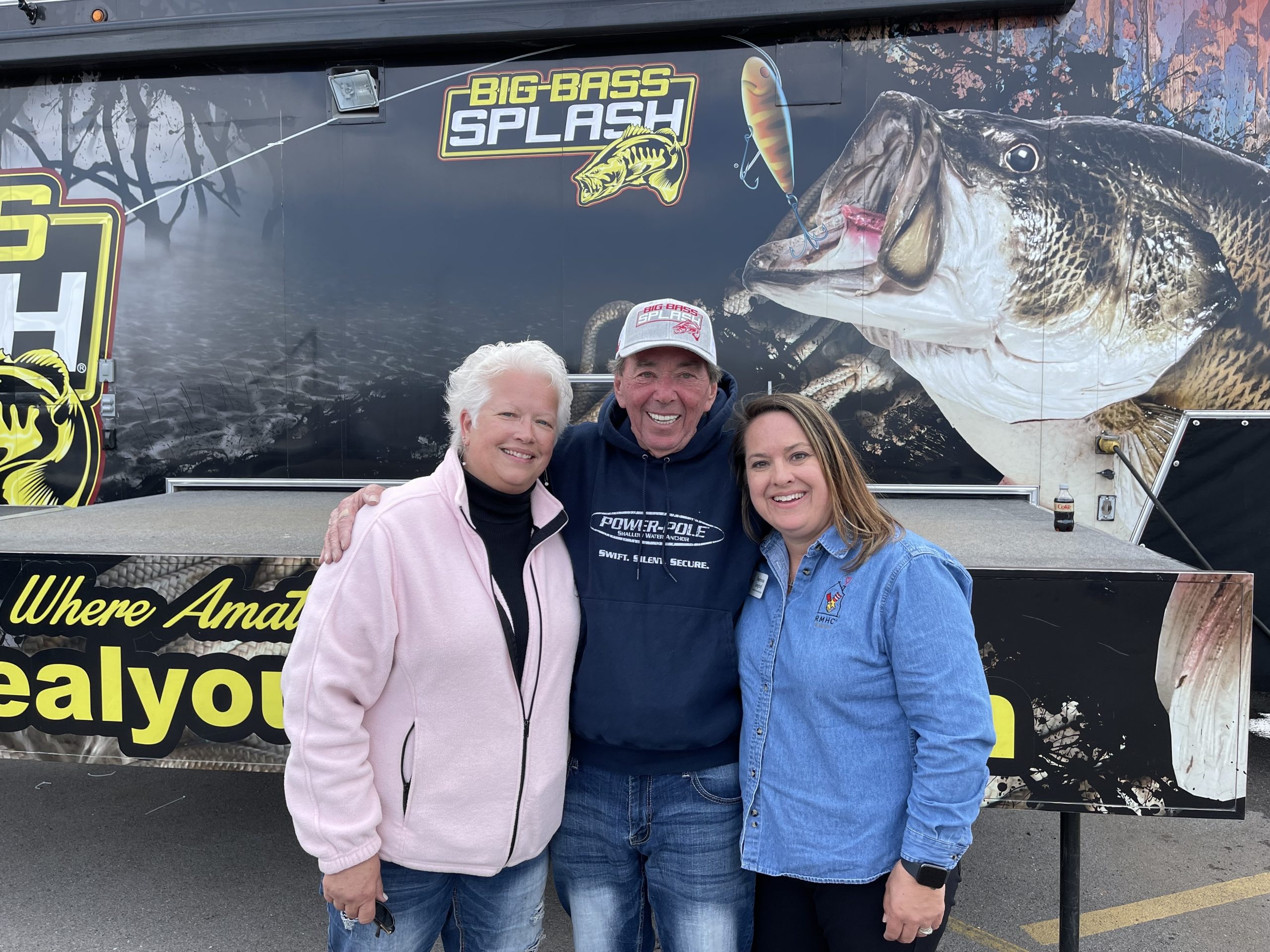 three people standing in front of a Big Bass Splash sign