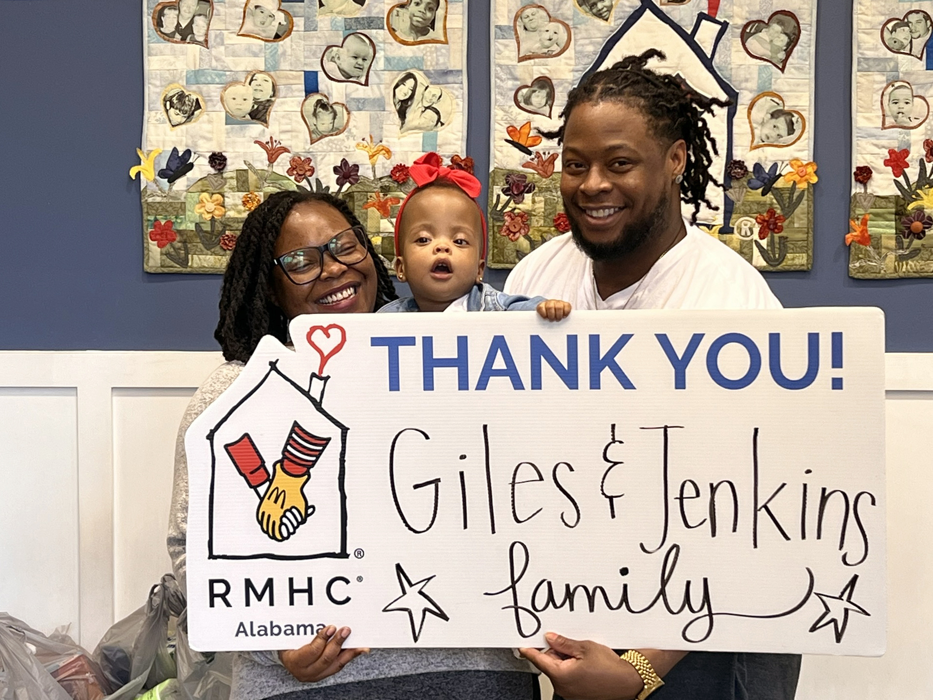 A family of 3 holding a Thank You sign that says Giles & Jenkins Family