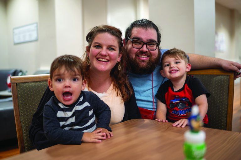 A mom, dad and two boys sit at a table