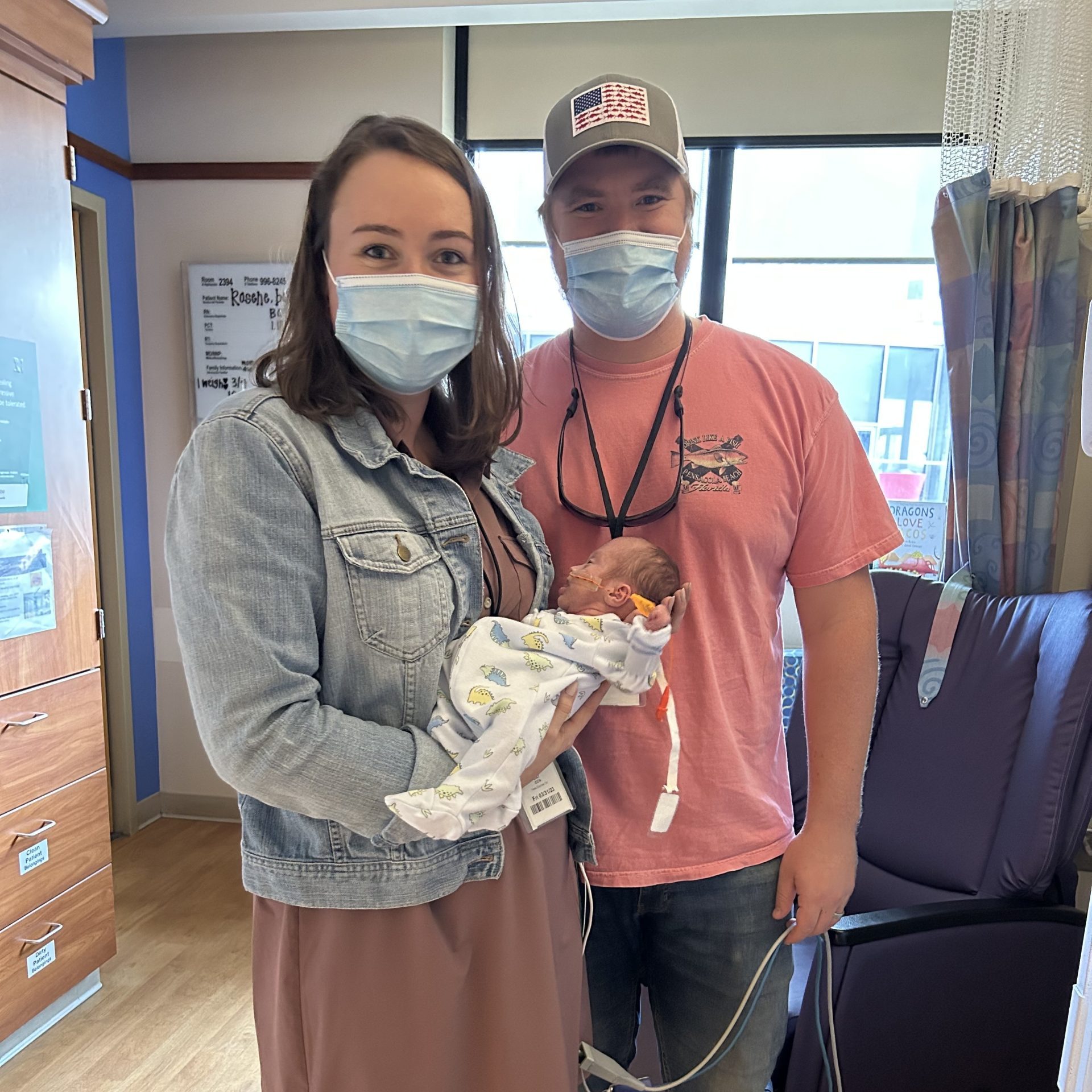 A mother and father hold their infant in the hospital