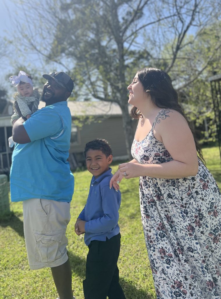 Family of three smiling on a sunny day