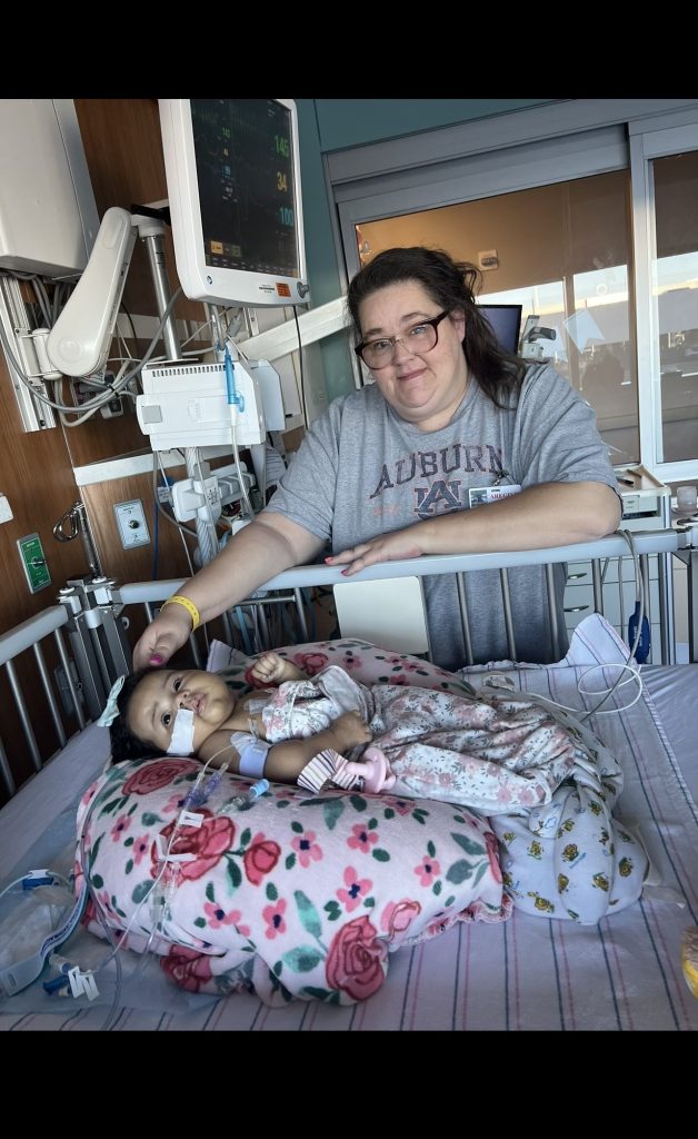 Shayla in a hospital bed while grandmother stands over her.